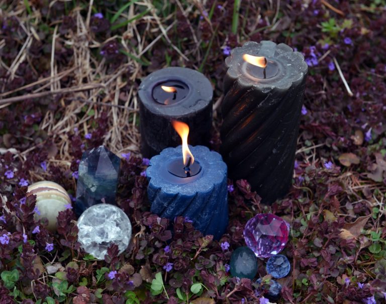 Beltane magic ritual with burning candles, crystals and magic objects outside.